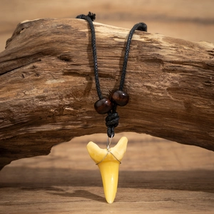 Détail d'un pendentif dent de requin avec perles en bois sur collier tressé noir