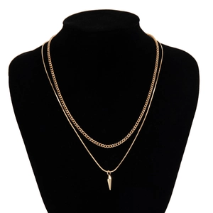 Detail of gold double-layered necklace featuring a cuban link chain and spiked cone pendant