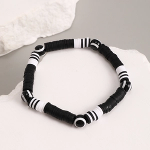 Close-up of black and white heishi clay bead bracelet with striped round accents
