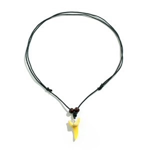Détail du collier en cordon tressé tribal avec perles en bois et pendentif dent de requin