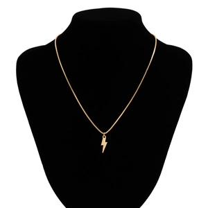 Detailed close-up of a gold lightning bolt pendant necklace on a black velvet neck bust