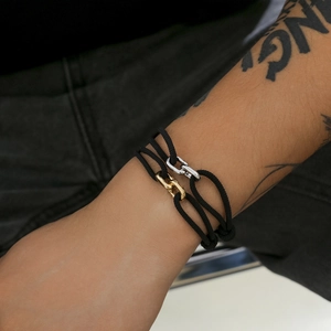 Minimalist black Milanese rope bracelet with gold and silver metal buckles on wrist