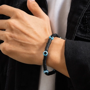 Men's bohemian black heishi bead bracelet with blue evil eye charms on a model wrist