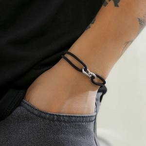 Detail of men's double-strand black woven bracelet with silver metal clasp on wrist