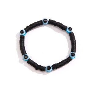 Detail of beaded bracelet with black Heishi discs and blue evil eye charms on white background