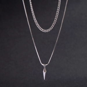 Close-up of silver layered necklace featuring a sleek spike pendant and polished chain detail