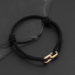 Close-up of black braided rope bracelet featuring interlocking gold polished metal links