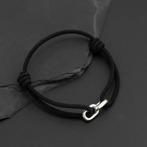 Close-up of black braided cord bracelet featuring a polished silver metal interlocking clasp