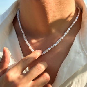 Close-up of baroque pearl necklace for men styled with a white satin shirt collar