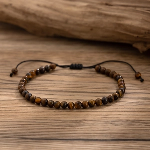 Detailed close-up of tiger eye stone beads on a black hand-woven adjustable anklet
