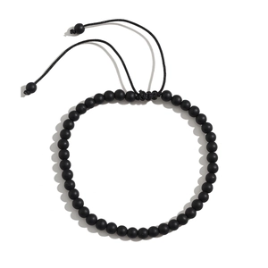 Detail of matte black tiger stone beads on a beach anklet with adjustable cord