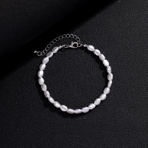 Detail of baroque pearl bracelet with silver lobster clasp on black leather background