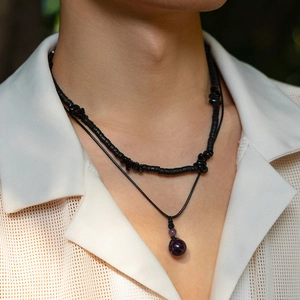 Dettaglio della collana hip hop da uomo con perle in legno nero e pendente in cristallo
