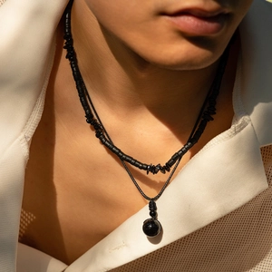 Dettaglio della collana a strati hip hop da uomo con perle nere e ciondolo a sfera
