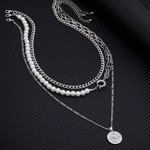 Gros plan d'un collier multicouche en argent avec perles et pendentif boussole