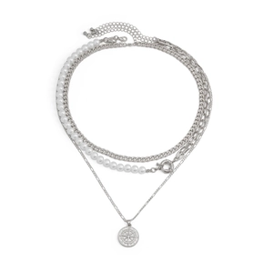 Détail d'un collier multicouche argenté avec perles blanches et pendentif boussole