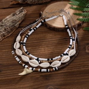Detail of bohemian layered necklace set with shell beads and ivory-colored tooth pendant