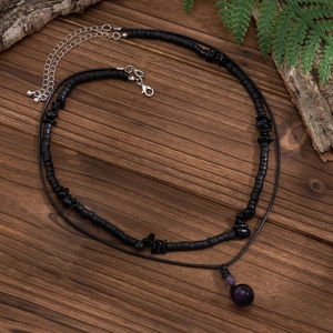 Dettaglio della collana a due strati con perle nere e un ciondolo rotondo viola