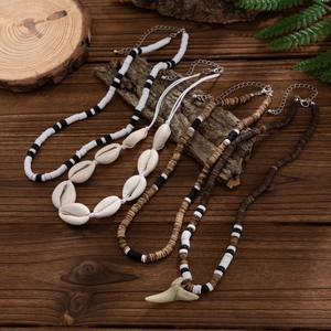 Set of 4 Bohemian coconut shell beaded necklaces with shark tooth pendant on wood background