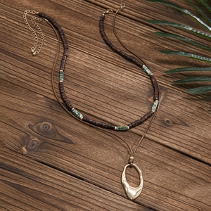 Close-up of bohemian double-layer necklace with wood beads and gold hollow pendant