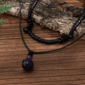 Collana hip hop da uomo con ciondolo in cristallo viola su fondo in legno scuro