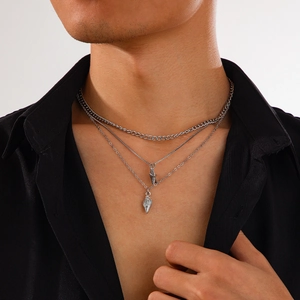 Gros plan d'un collier argenté à trois couches avec pendentifs coquillage sur chemise noire