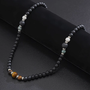 Detail of beaded necklace featuring natural tiger eye and lava stone on a dark display
