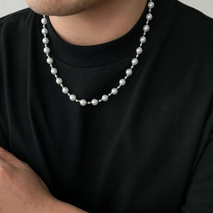 Men's hip-hop pearl necklace with green accent beads worn on a black t-shirt neckline