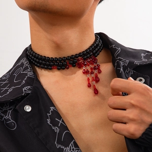 Gros plan d'un collier à trois rangs de perles noires avec pampilles rouges sur un mannequin