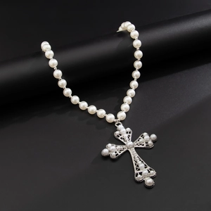 Détail d'un pendentif croix vintage argenté avec perles blanches sur collier élégant