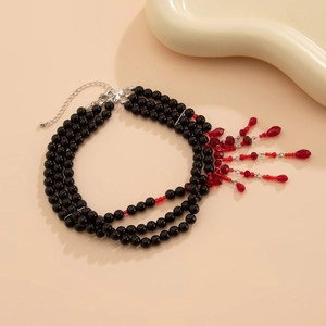 Détail de perles noires multicouches avec pendentifs gouttes rouges et fermoir argent