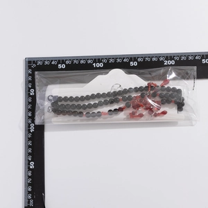 Détail du collier de perles avec pendentif goutte de sang et échelle de mesure