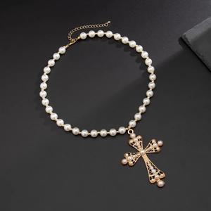 Collier rétro avec pendentif croix en perles blanches et métal doré sur fond gris mat