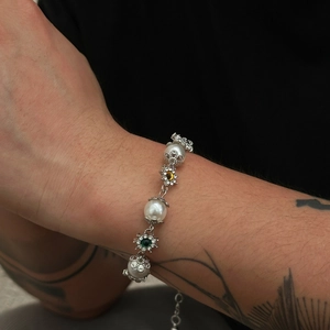 Gros plan du bracelet de perles avec chaîne argentée et breloques fleurs sur modèle