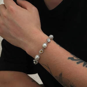 Détail du bracelet en perles pour hommes avec breloques florales et gemmes argentées