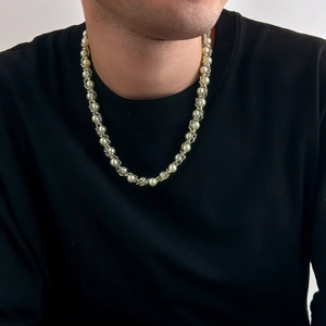 Detail einer goldfarbenen Metallkette mit weißen Kunstperlen auf schwarzem Hemd
