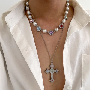 Dettaglio della collana di perle a strati con ciondolo a cuore e croce d'argento