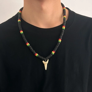 Dettaglio della collana con dente di squalo e perline di legno rosse, gialle e verdi