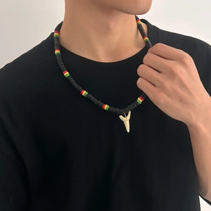 Dettaglio della collana da uomo con perline colorate e ciondolo a forma di dente di squalo