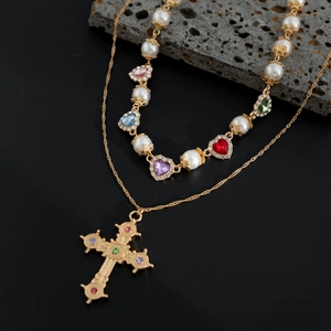Dettaglio collana a due strati con perle, pietre a cuore e ciondolo a croce vintage