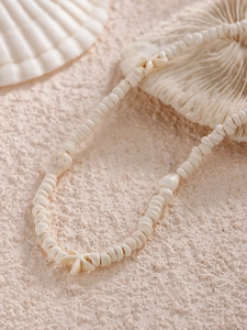 Détail macro d'un collier de perles océan avec pendentifs étoile de mer sur fond de plage