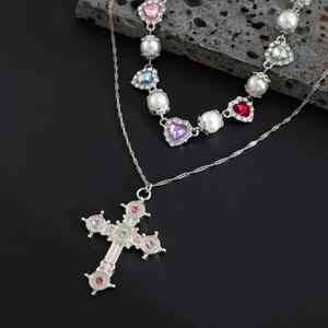 Dettaglio di collane in argento a strati con pietre a cuore, perle e un ciondolo a croce