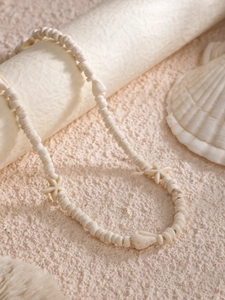 Détail d'un collier de plage avec perles crème, étoiles de mer et touches de coquillage