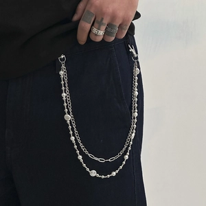 Detail of layered hip-hop trouser chain with silver links and white faux pearls on jeans