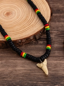 Dettaglio della collana di perline in legno con ciondolo a dente di squalo e perline colorate