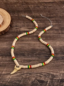 Dettaglio della collana con dente di squalo e perline di legno colorate su sfondo scuro