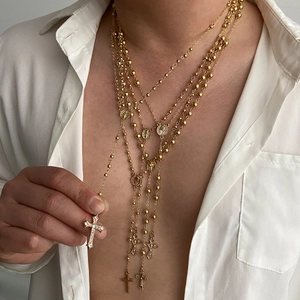 Vijfdelige gouden kruisketting set met religieuze medaillons op een wit overhemd