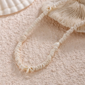 Collier de perles disque avec étoile de mer et coquillage sur sable marin