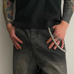 Detail of hip hop faux pearl trouser chain with metal hooks on grey denim jeans