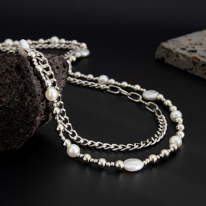 Close-up of hip-hop waist chain with pearls and silver links on black volcanic stone